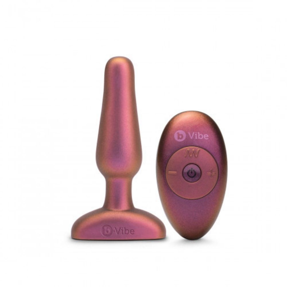 B-Vibe Novice Plug - Limited Edition Galaxy Plum standing upright on base with the remote control it comes with