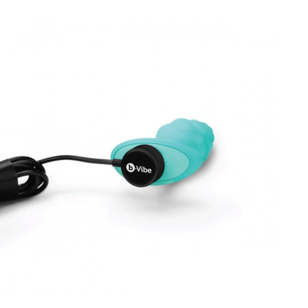 B-Vibe Texture Plug Bump Aqua (Small) laying flat with the charger plugged into its base