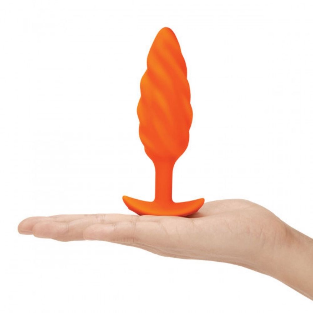 B-Vibe Texture Plug Swirl Orange (Medium) standing upright on top of the palm of a hand