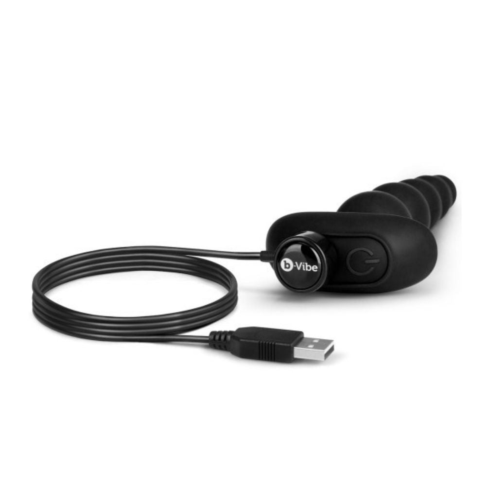 B-Vibe Cinco Beads laying flat with the charging cable plugged into its base at the forefront