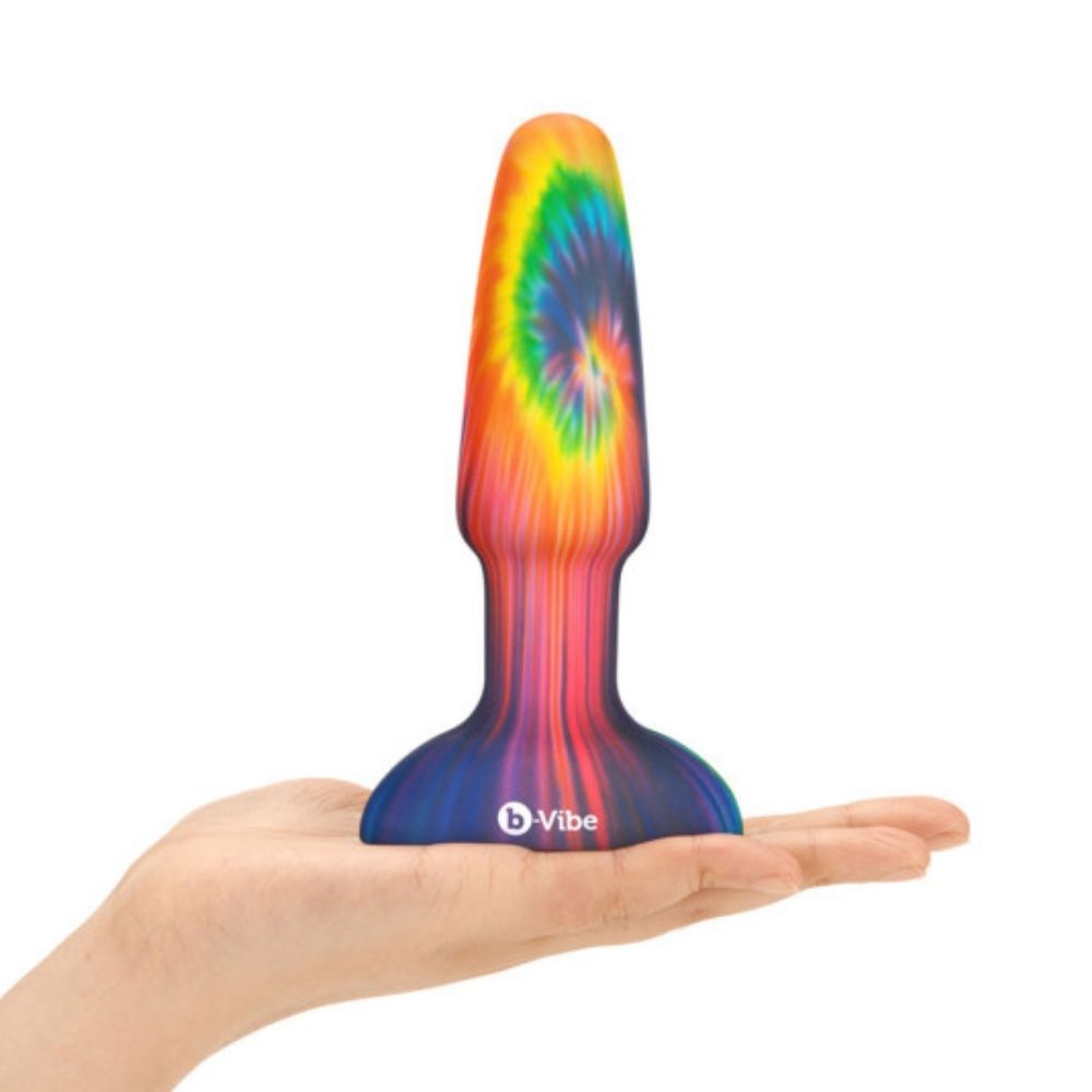 B-Vibe Peace & Love Tie Dye Rimming Plug standing upright on base in the palm of a hand