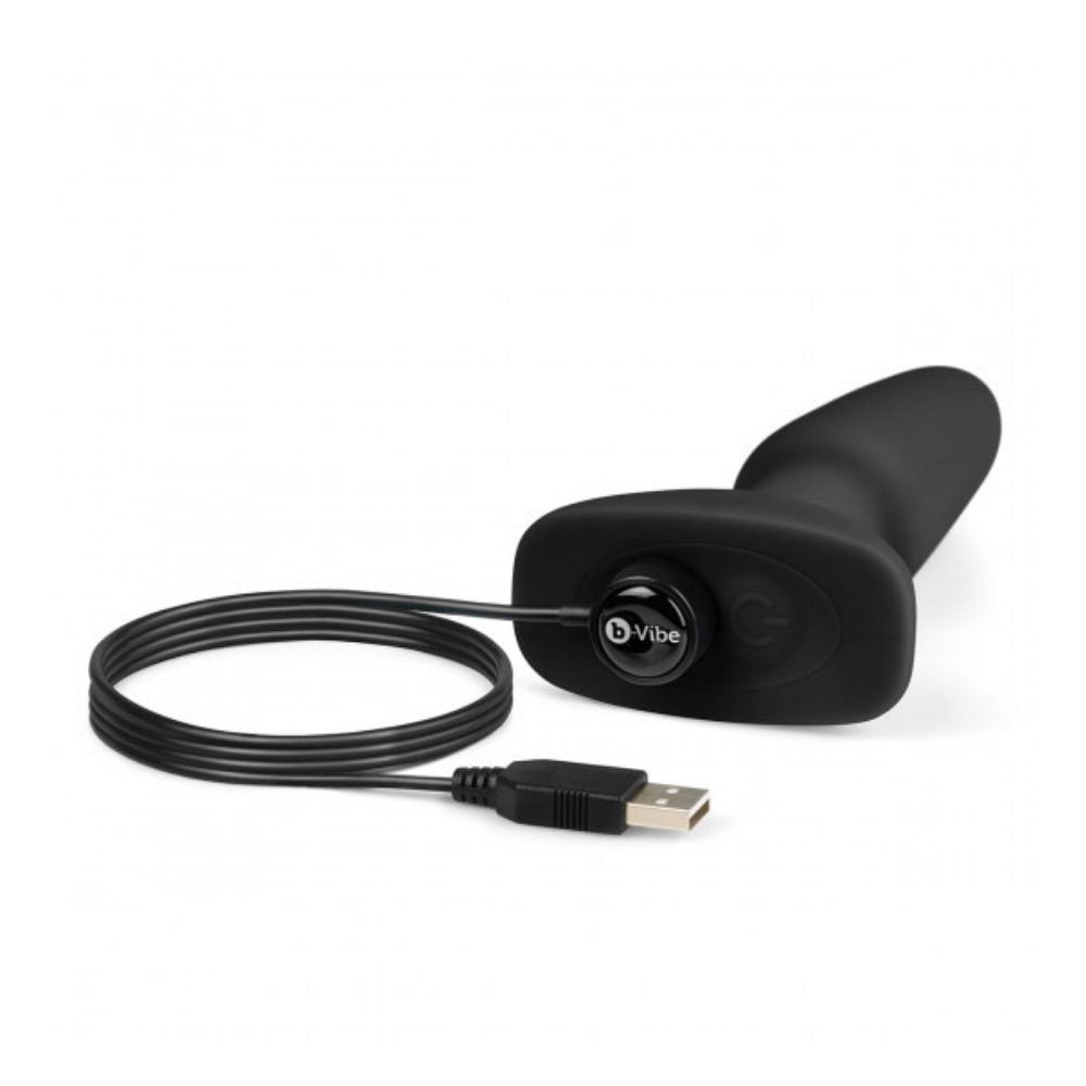 Black B-Vibe Rimming Plug 2 laying flat on its side with the charger plugged into its base