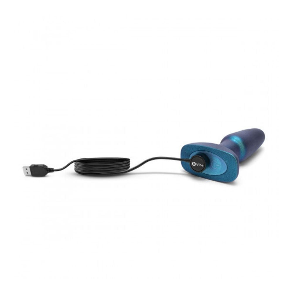 B-Vibe Rimming Plug 2 - Limited Edition Space Green laying flat on its side with the charging cable plugged into its base