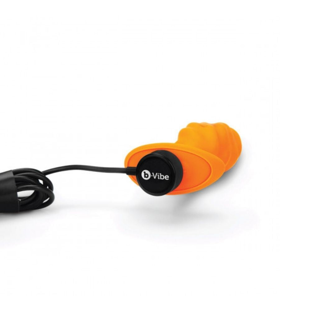 B-Vibe Texture Plug Swirl Orange (Medium) laying flat on its side with the charger plugged into its base