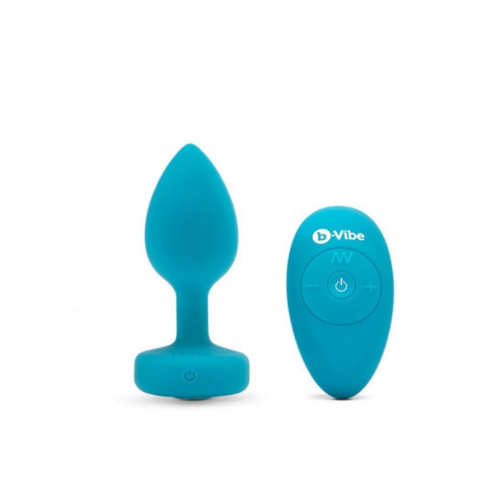 Aqua B-Vibe Vibrating Jewel Plug Small/Medium  standing upright on its base beside the remote control it comes with