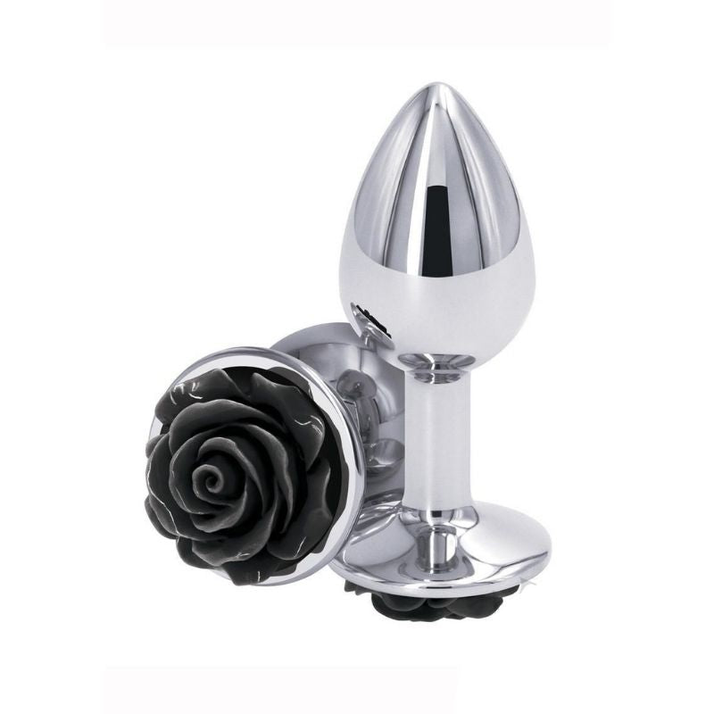 Two Medium Rear Assets Rose Anal Plugs with a black rose base and silver colored body. One positioned on side showing the black rose base, the other standing upright on base