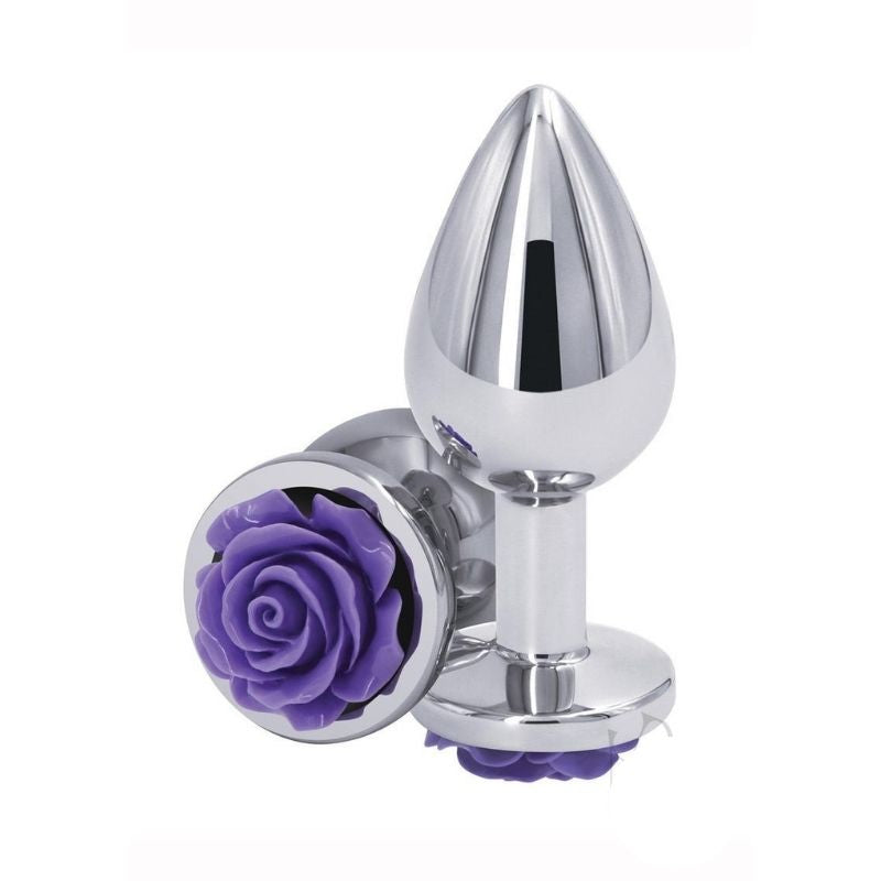 Two Medium Rear Assets Rose Anal Plugs with a purple rose base and silver colored body. One positioned on side showing the purple rose base, the other standing upright on base